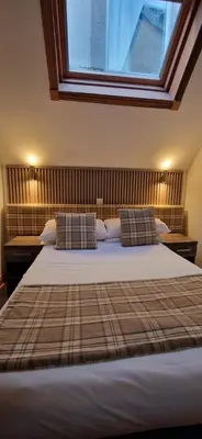 a bedroom with a bed with pillows and a window at Loch Long Hotel in Arrochar