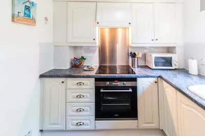 a kitchen with white cabinets and a stove top oven at Mycosy 605 in Paisley