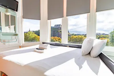 a bedroom with a large white bed with windows at easyHotel Edinburgh in Edinburgh