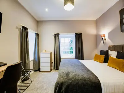 a bedroom with a bed and a desk and a window at Barony Castle Hotel in Peebles