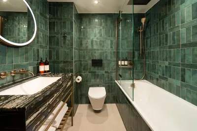 a green tiled bathroom with a tub and a toilet at Carlton George Hotel in Glasgow