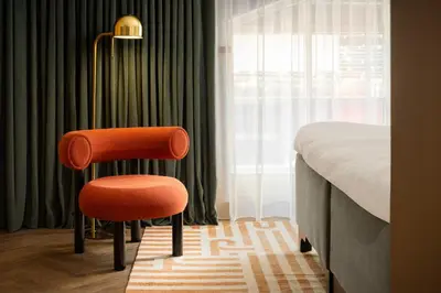 an orange chair sitting next to a bed in a room at Carlton George Hotel in Glasgow