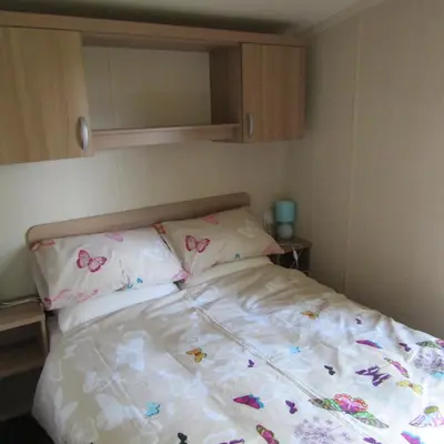 a bed in a bedroom with butterflies on it at Barnkirk Holidays in Newton Stewart