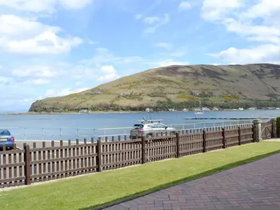 a car parked next to a fence near a body of water at The Shieling in Lochranza