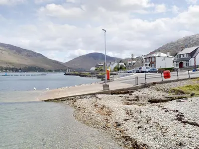 a body of water with a pier and houses at The Shieling in Lochranza