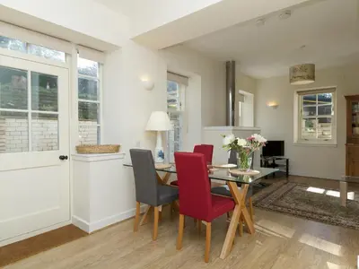 a dining room with a table and red chairs at Two The Stables in Dalrymple
