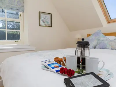 a bed with a table with a tablet on it at Two The Stables in Dalrymple