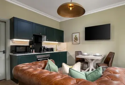 a living room with a couch and a kitchen at Munro Guest House in Stirling
