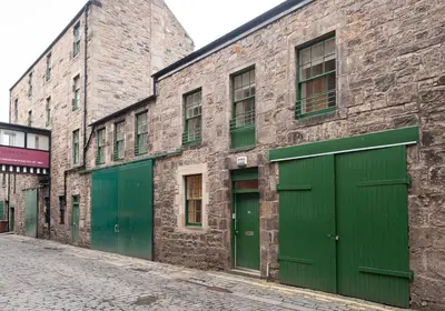 a brick building with green doors on a street at Apartment Thistle Lane in Edinburgh