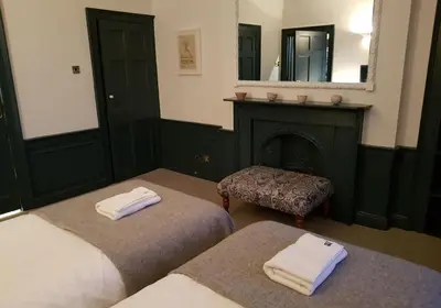 a bedroom with two beds and a fireplace and a mirror at Thistle Suite city centre in Edinburgh