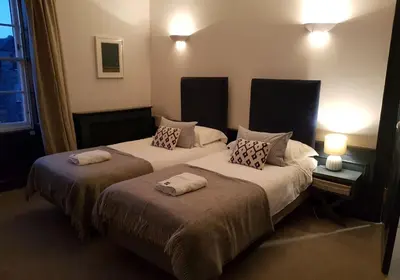two beds in a hotel room with two lamps at Thistle Suite city centre in Edinburgh