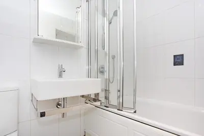 a white bathroom with a sink and a shower at Broompark House in Glasgow