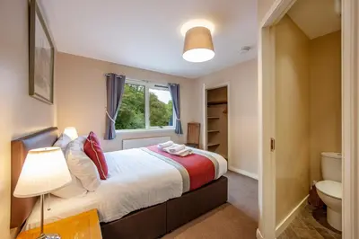 a bedroom with a bed and a toilet and a window at Wildwood Cottage with Hot Tub in Glencoe