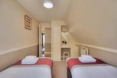 two twin beds in a small room with a kitchen at Loch Linnhe Waterfront Lodges with Hot Tubs in Glencoe