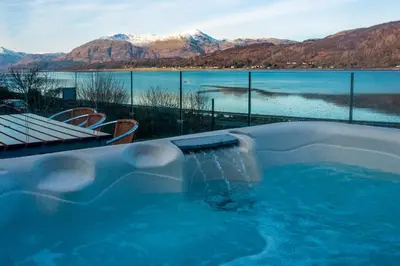 a swimming pool with a view of a lake and mountains at Glenachulish Bay with Hot Tub in Glencoe