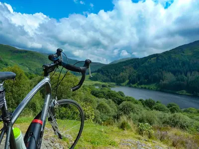a bike parked on a hill with a view of a river at Culsharg Cottage in Bargrennan