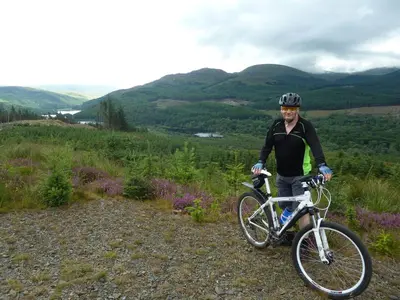 a man standing next to a bike on a hill at Culsharg Cottage in Bargrennan