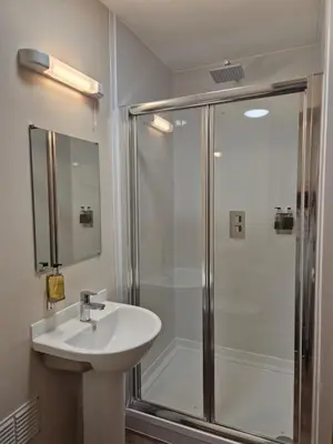 a white bathroom with a shower and a sink at Douglas Hotel in Glasgow