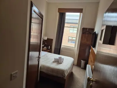 a small bedroom with a bed and a window at Douglas Hotel in Glasgow