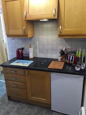 a kitchen with wooden cabinets and a black counter top at Artisan Studio in Tarbert