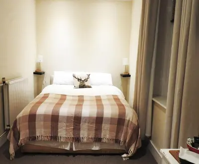 a bedroom with a bed with a plaid blanket at The Stag Head Hotel in Edinburgh