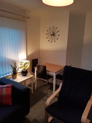 a living room with a table and chairs and a clock at Bathgate Contractor and Business Apartment in Bathgate