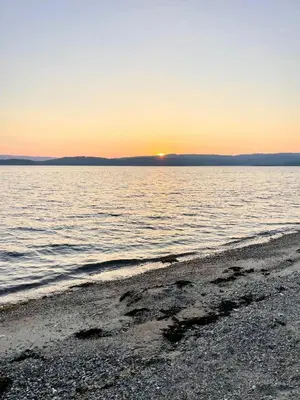 a beach with the sun setting over the water at Cockleshell Lodge in Otter Ferry