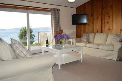 a living room with a couch and a table with a bottle of wine at Cockleshell Lodge in Otter Ferry