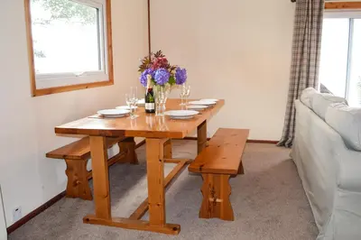 a wooden table with wine glasses and flowers on it at Cockleshell Lodge in Otter Ferry
