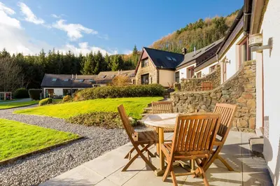 a patio with a table and chairs and a stone wall at Melfort Village in Oban