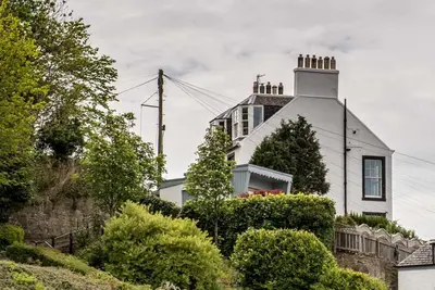 a white house with a chimney on top of a hill at Forth Reflections Self Catering in Queensferry