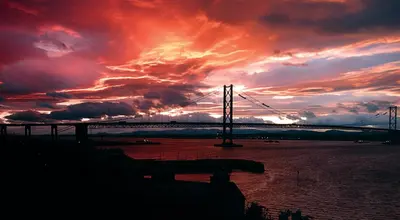 a bridge over the water with a sunset at Forth Reflections Self Catering in Queensferry