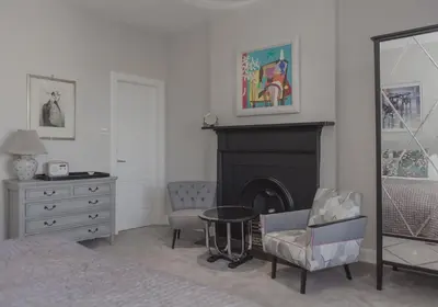 a bedroom with a fireplace and a chair and a mirror at The Skyline - The Edinburgh Address in Edinburgh