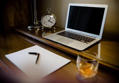 a desk with a laptop computer and a glass of water and a clock at The Edinburgh Address - Castle View Apartment in Edinburgh
