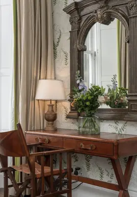 a mirror and a desk with a lamp and a chair at The Edinburgh Address - Castle View Apartment in Edinburgh