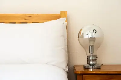 a light bulb on a table next to a bed at Rose Street - Watchmakers Apartment in Edinburgh
