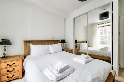 a bedroom with a large white bed and a mirror at Rose Street - Watchmakers Apartment in Edinburgh