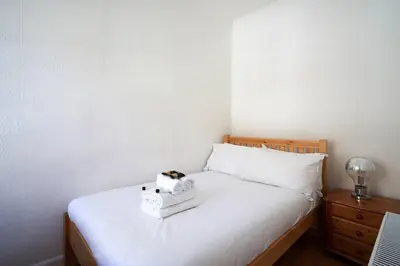 a bedroom with a white bed with a stuffed animal on it at Rose Street - Watchmakers Apartment in Edinburgh