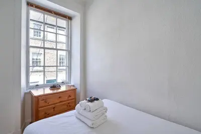 a white bedroom with a bed with towels on it at Rose Street - Watchmakers Apartment in Edinburgh