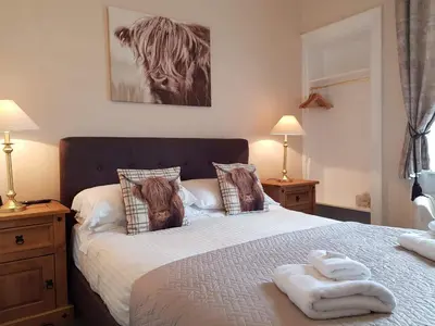 a bedroom with a large bed with two lamps and towels on it at Brig O'Doon Guest House in Edinburgh