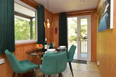 a dining room with a table and green chairs at Ash Lodge in Benmore