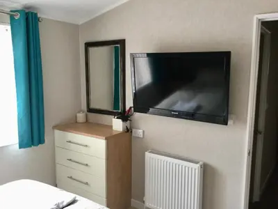 a bedroom with a large flat screen tv on the wall at Rannoch Lodge in Auchterarder