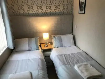 two beds in a room with a lamp on a table at Rannoch Lodge in Auchterarder