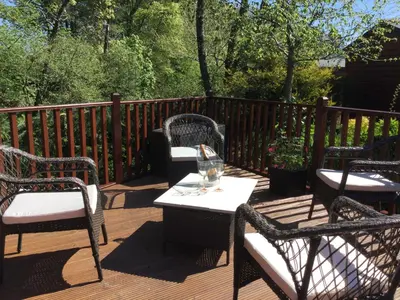 a deck with three chairs and a table with a wine glass at Rannoch Lodge in Auchterarder