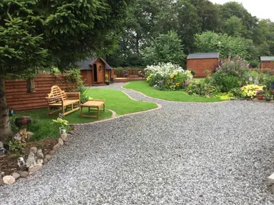 a garden with a gravel path and a bench at Rannoch Lodge in Auchterarder