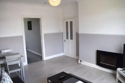 a living room with white walls and a fireplace at Kelpies Serviced Apartments - Wallace in Falkirk
