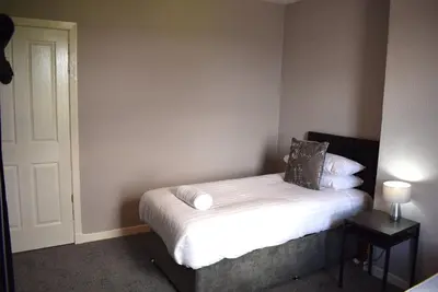 a small bedroom with a bed with white sheets and pillows at Kelpies Serviced Apartments - Wallace in Falkirk