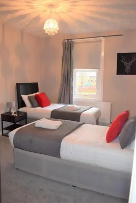 a bedroom with two beds and a window at Kelpies Serviced Apartments - Wallace in Falkirk