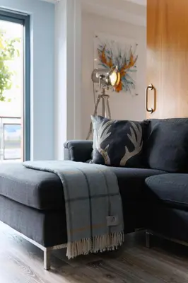 a living room with a blue couch with a ottoman at Riverside West End Apartment in Glasgow