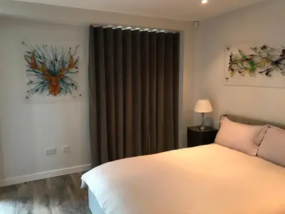 a bedroom with a bed and a window with curtains at Riverside West End Apartment in Glasgow